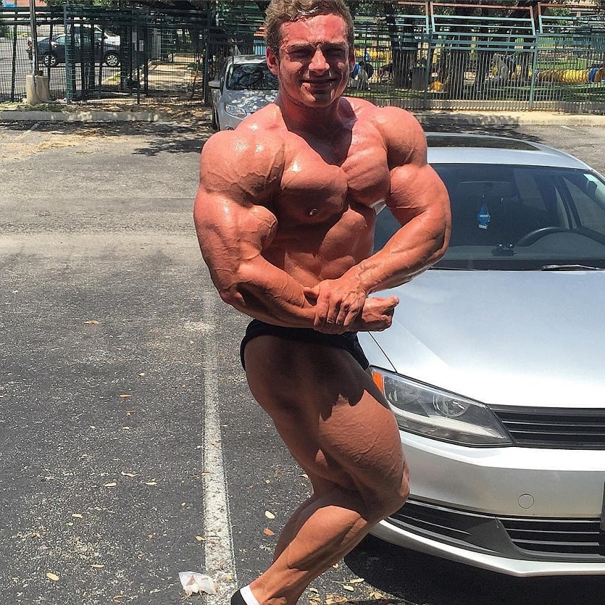 Cody Montgomery doing a shirtless side chest pose outdoors by his car