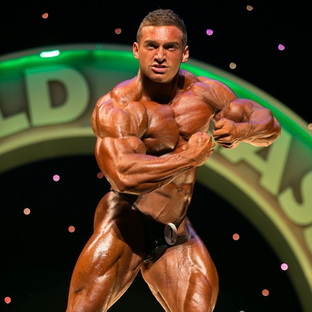 Cody Montgomery posing on a bodybuilding stage looking big and muscular