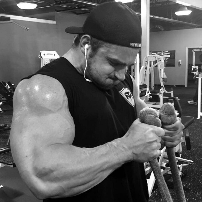 Cody Montgomery doing cable hammer curls his arms looking huge