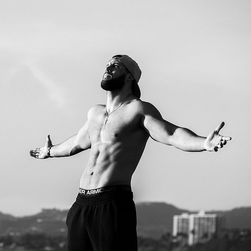 Florian Munteanu standing with his arms raised in the air looking happy healthy and lean