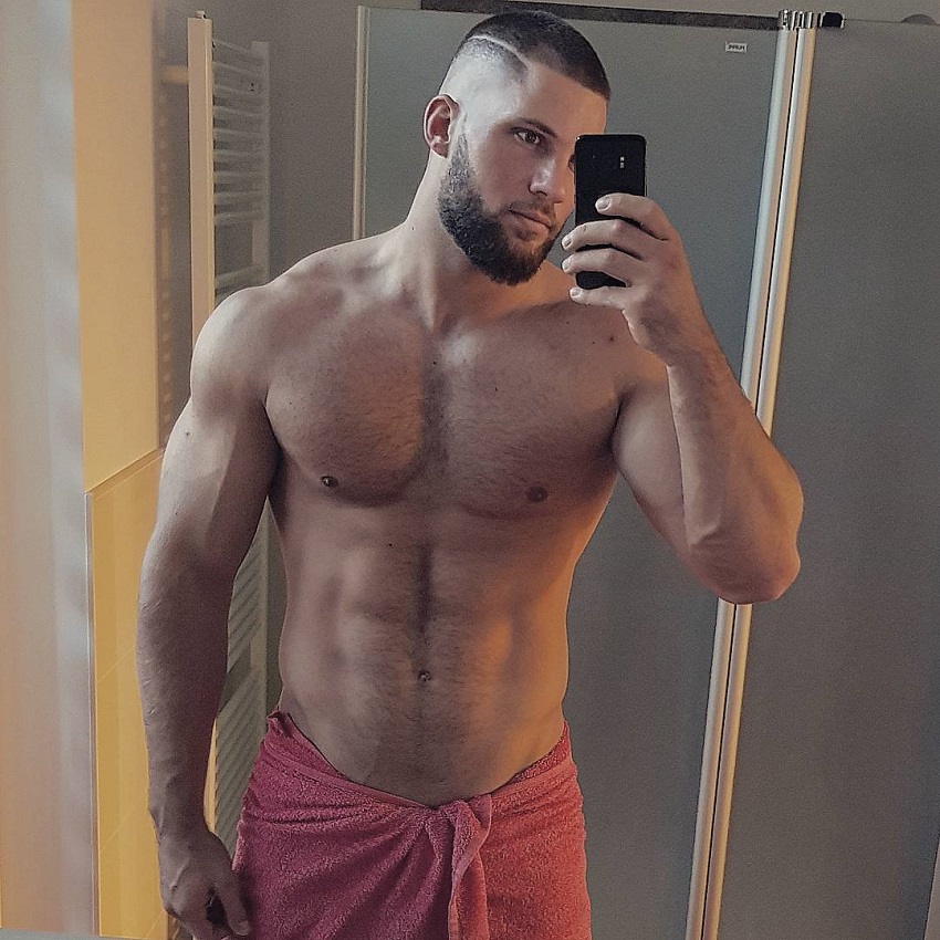 Florian Munteanu taking a selfie of his muscular upper body