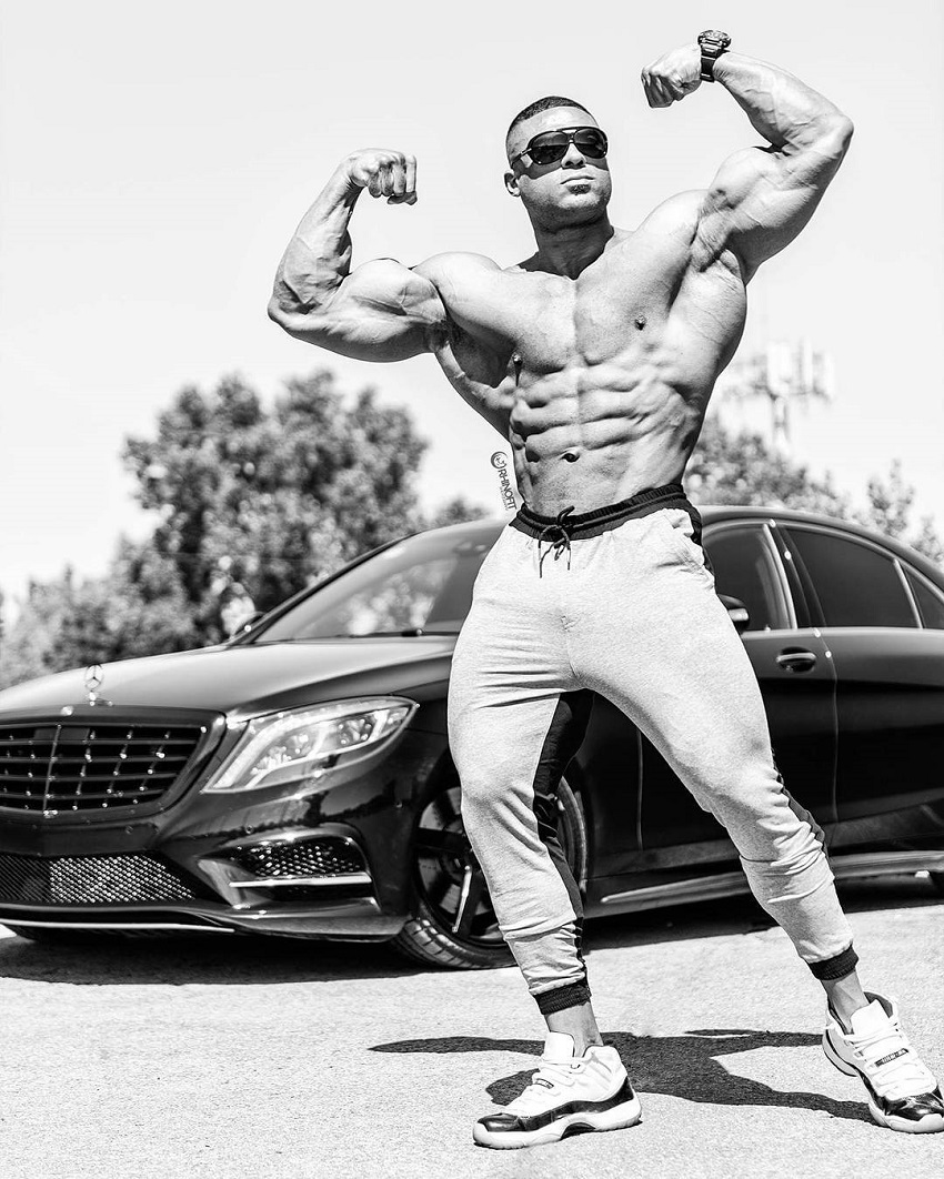 Henri-Pierre Ano flexing his biceps in front of his luxurious car