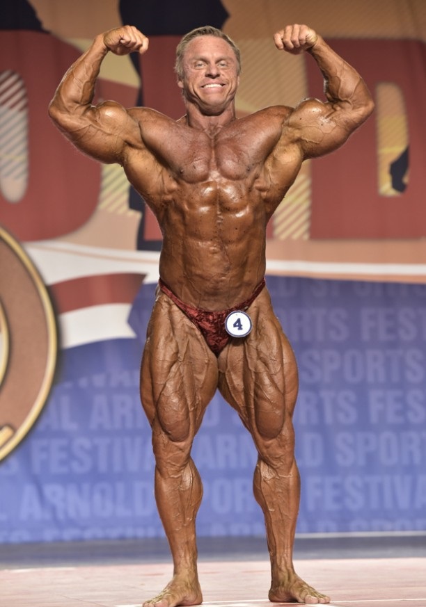 John Meadows doing a frount double biceps pose on a bodybuilding stage