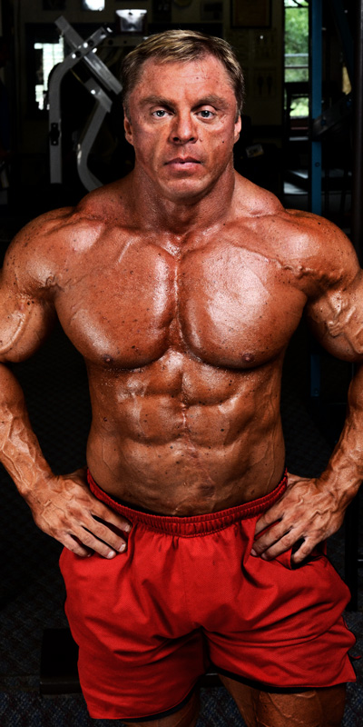 John Meadows posing shirtless for a photo looking big and ripped