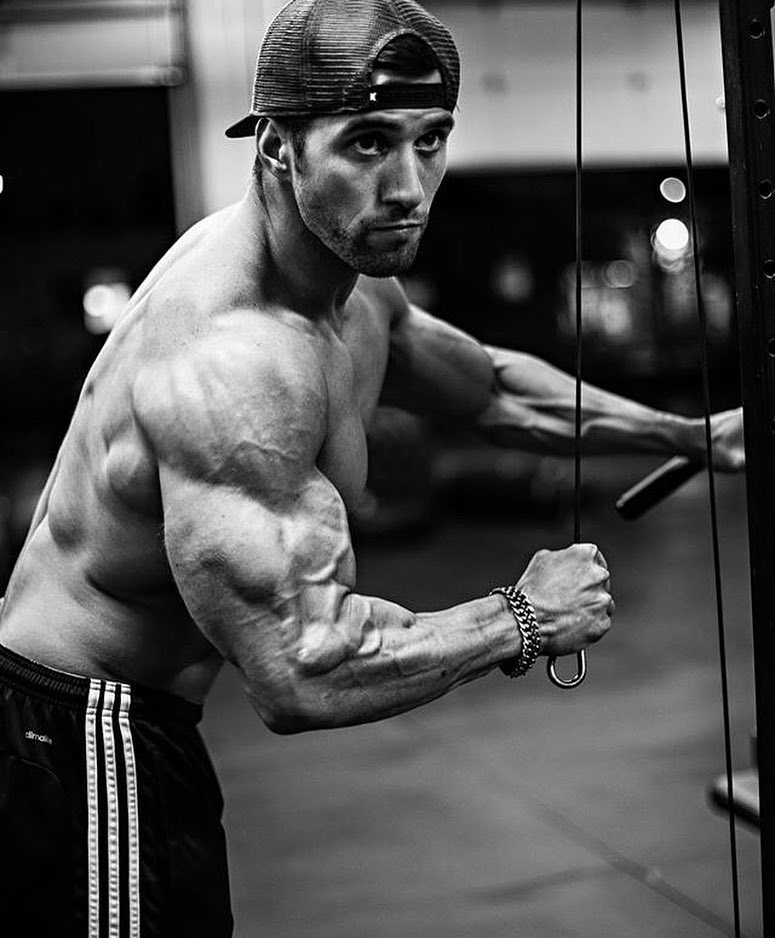 Julian Smith training shirtless with cables in a gym looking ripped