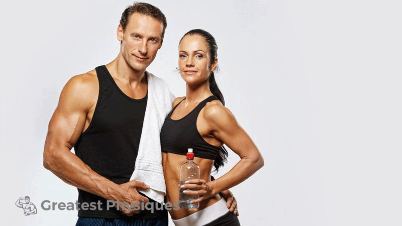 Toned and fit man and woman smiling at the camera in their gym wear
