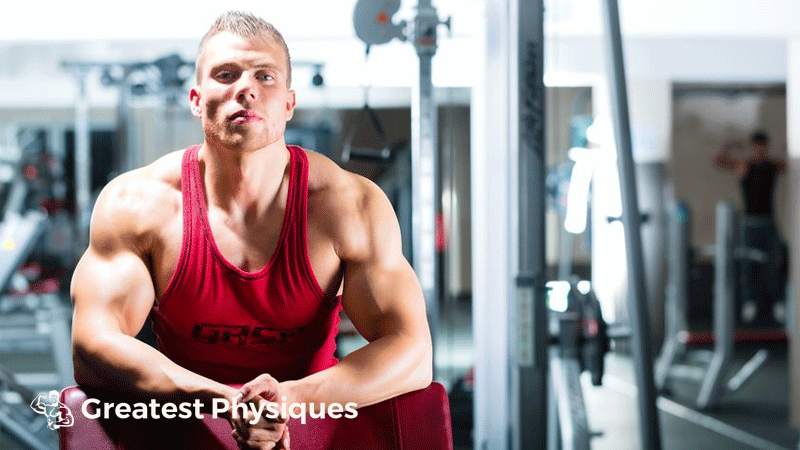 Athlete in red vest using a preacher bicep curl machine