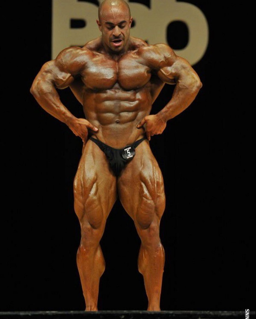 Sasan Heirati spreading his lats in a bodybuilding contest, looking big and ripped