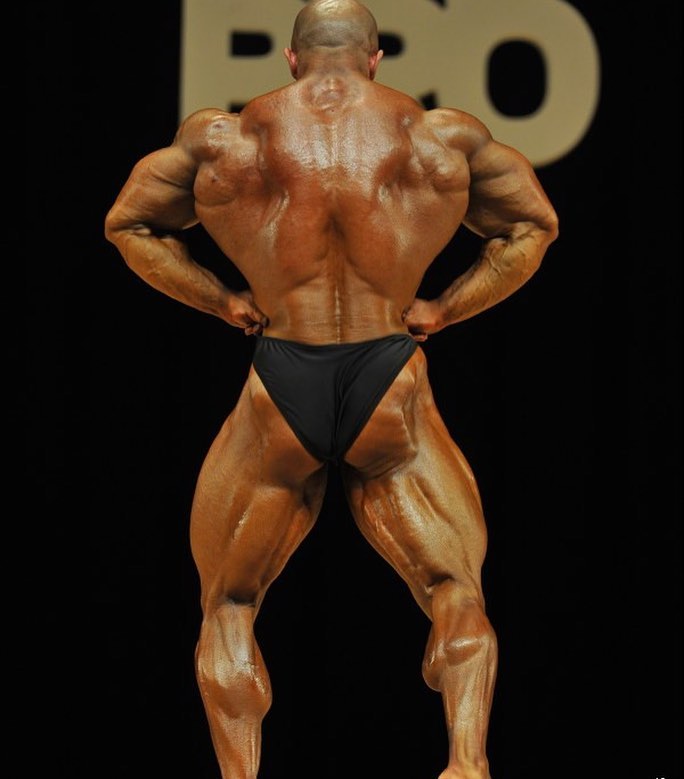 Sasan Heirati performing a rear lat spread pose on a bodybuilding stage