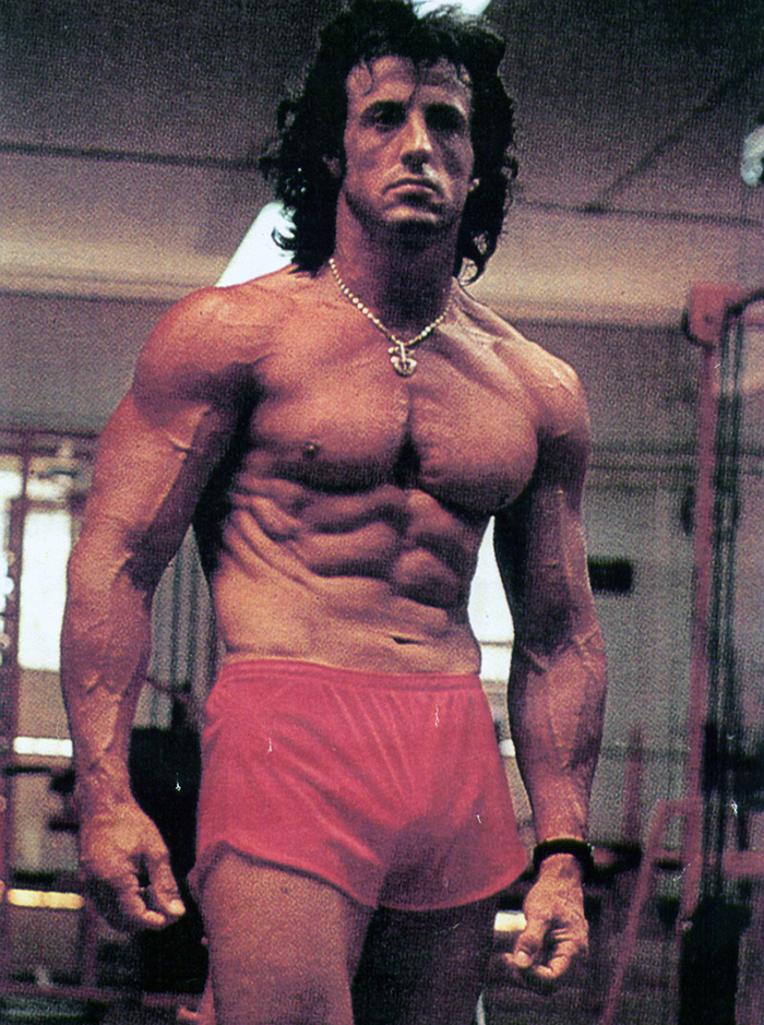 Sylvester Stallone looking incredibly ripped in the 70's wearing red shorts in the gym