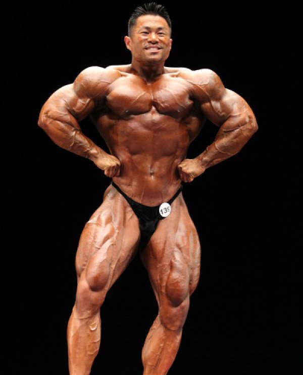 An Nguyen spreading his lats in front of the judges and auditorium on a bodybuilding stage