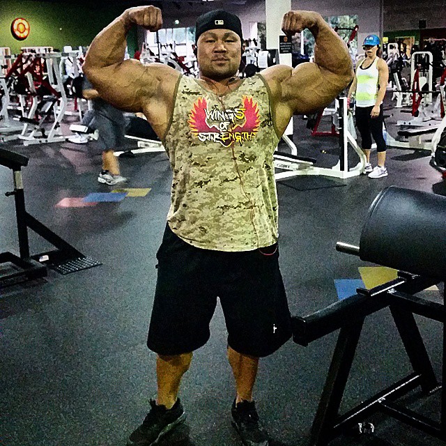 An Nguyen flexing his biceps in a gym for a photo