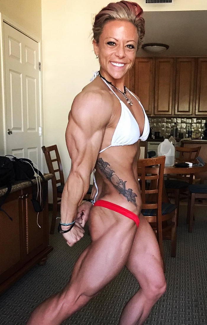 Dani Reardon flexing her triceps for a photo looking lean and aesthetic