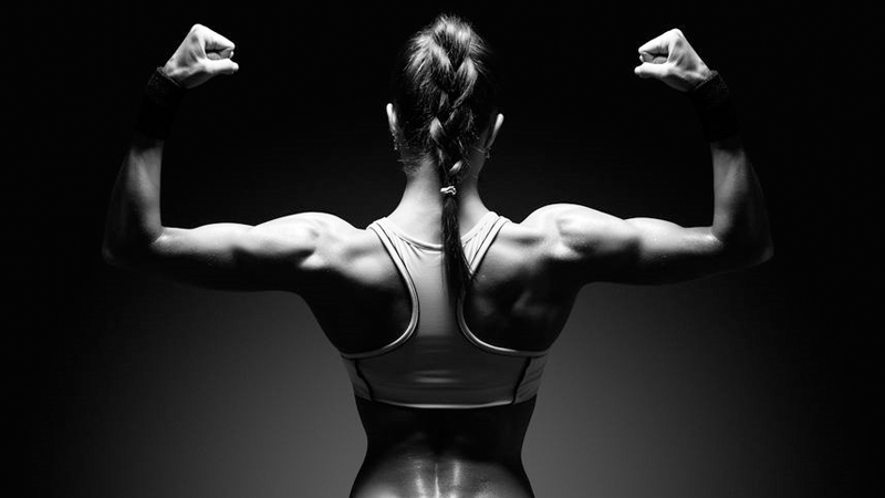 Black and white image of athletic woman performing double-bicep pose
