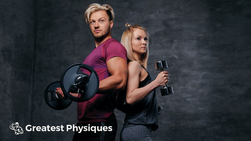 Attractive man and woman back-to-back in the gym lifting weights