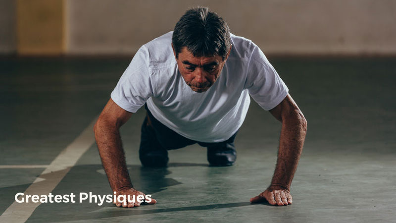 Older Hispanic man performing press-ups in the gym