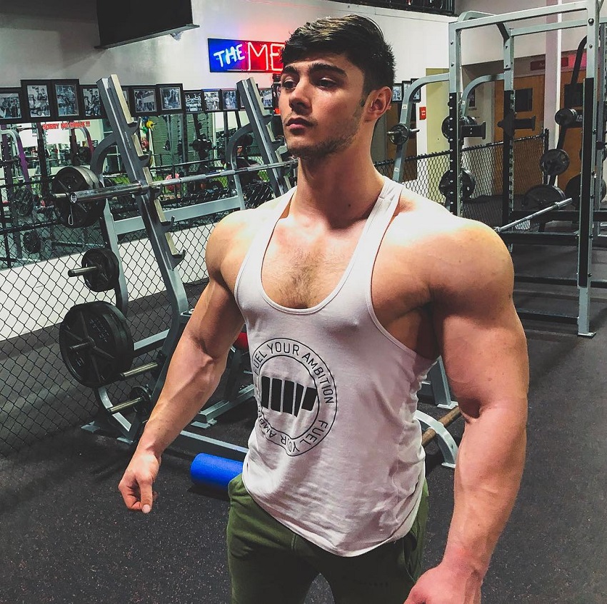 Qwin Vitale posing off in a white tank top in a gym looking healthy and fit