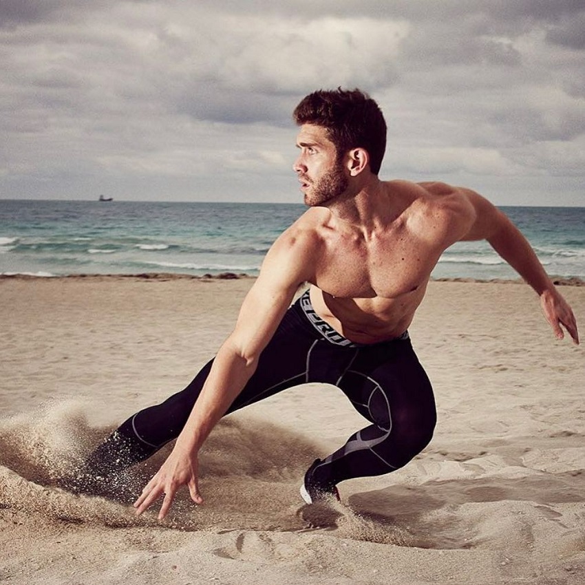 CJ Koegel running on a beach looking ripped and muscular