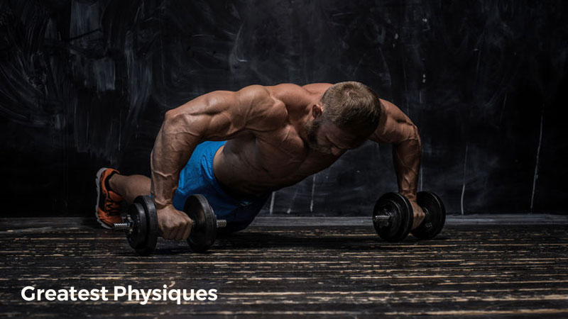 Bodybuilder in blue shorts performing dumbbell press-ups on the gym floor