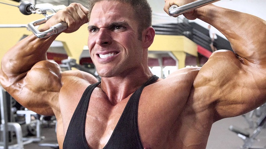 Josh Bergeron doing intense cable biceps curls in a gym looking big and riped