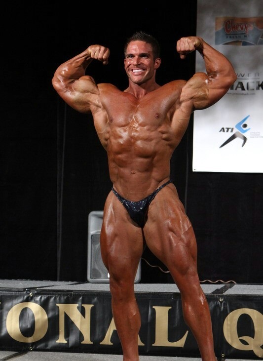 Josh Bergeron doing a front double biceps flex in front of the judges on a bodybuilding stage