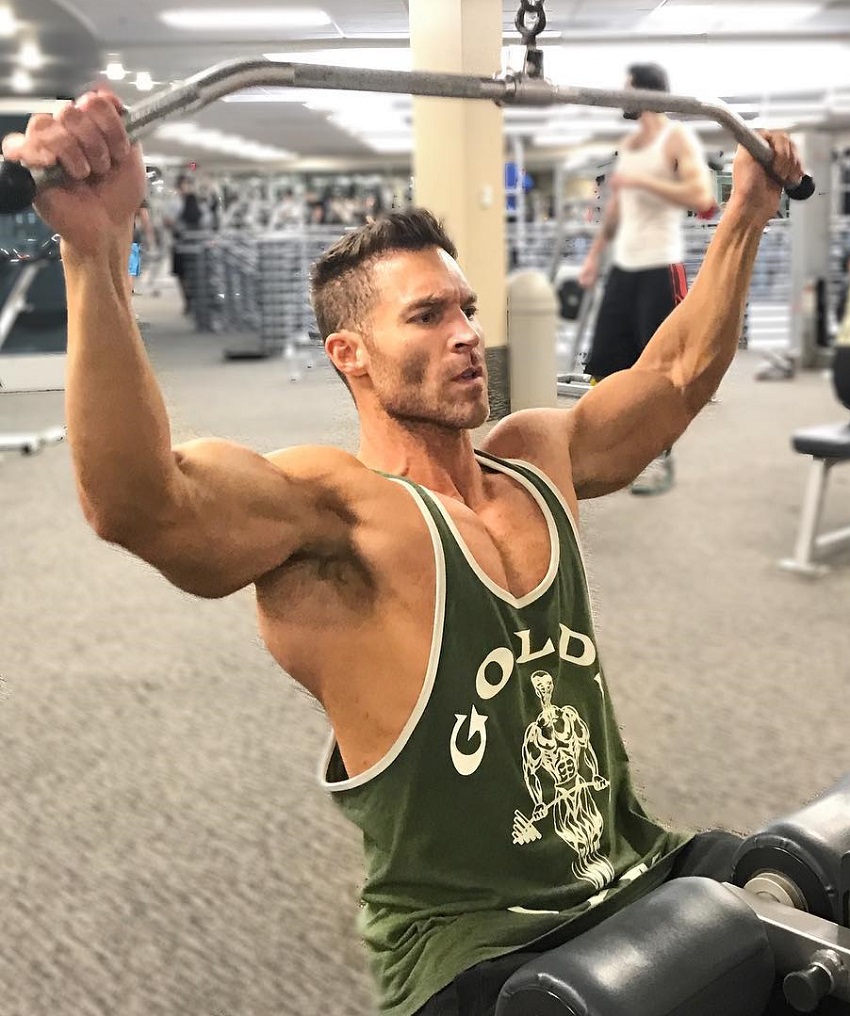 Kyle Clarke doing lat pulldowns weaing a green tank top