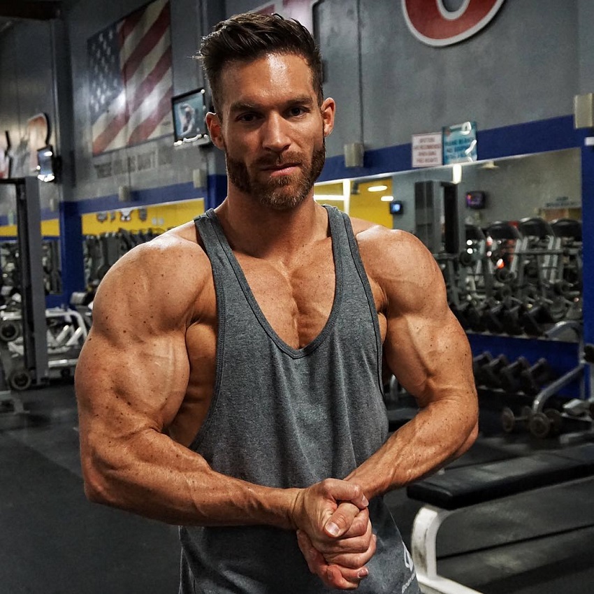 Kyle Clarke flexing his ripped muscles in a grey tank top