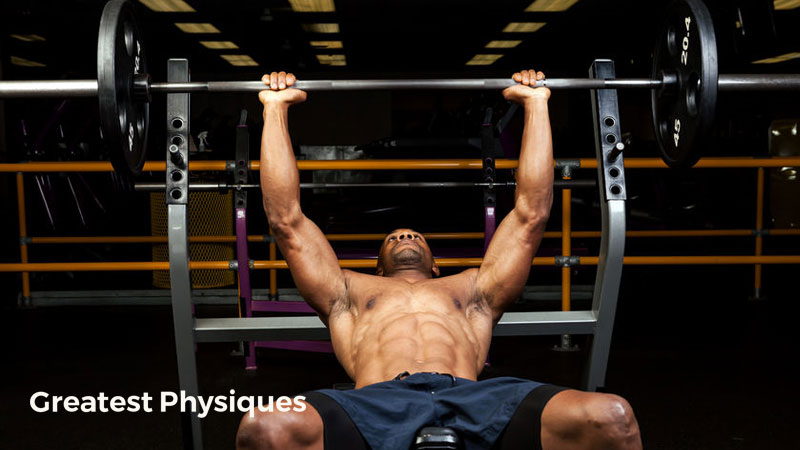 Muscular athletic man performing a bench press on dark background