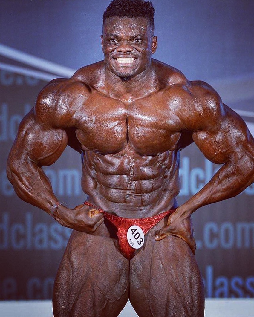 Blessing Awodibu doing a most muscular pose on a bodybuilding stage