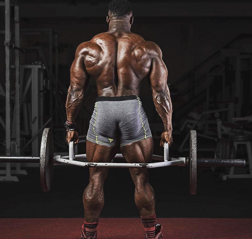 Blessing Awodibu lifting heavy weights in a photo shoot, his back looking big and strong