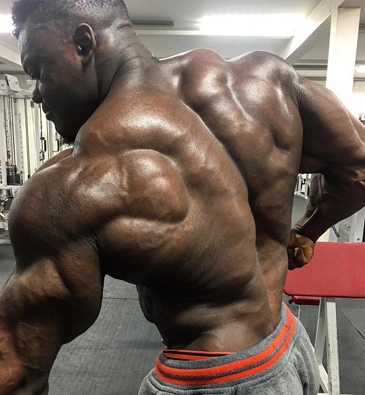 Blessing Awodibu flexing his ripped and huge back in a gym