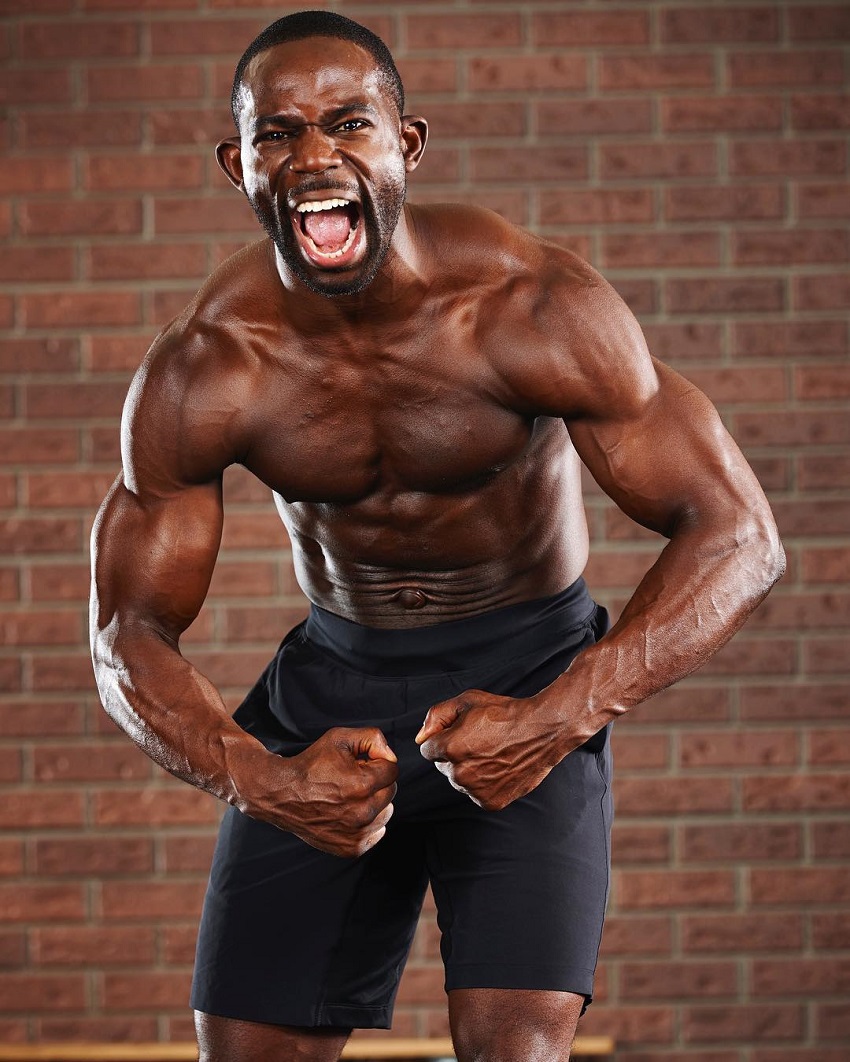 Gideon Akande flexing his muscles for a photo with a yelling grimace