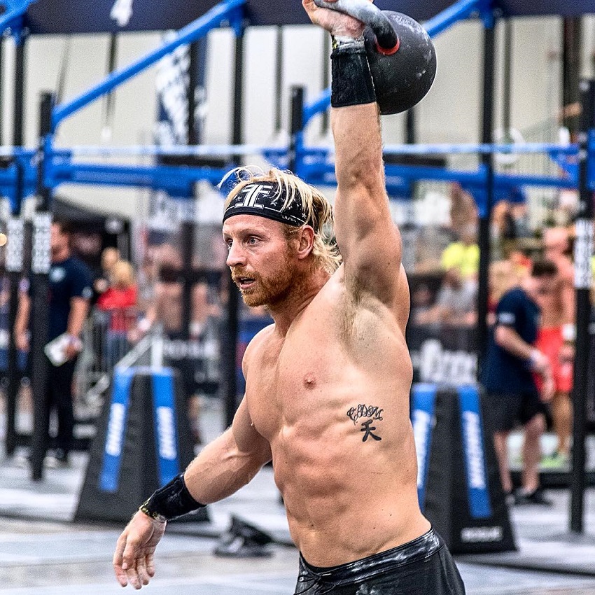 Graham Holmberg lifting a kettlebell over his head during a CrossFit competition