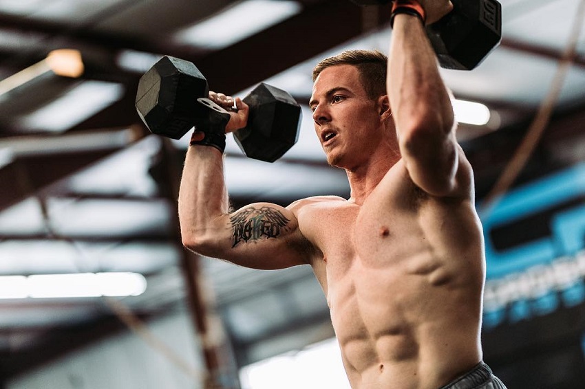 Noah Ohlsen training hard with dumbbells his shirtless body looking ripped and strong