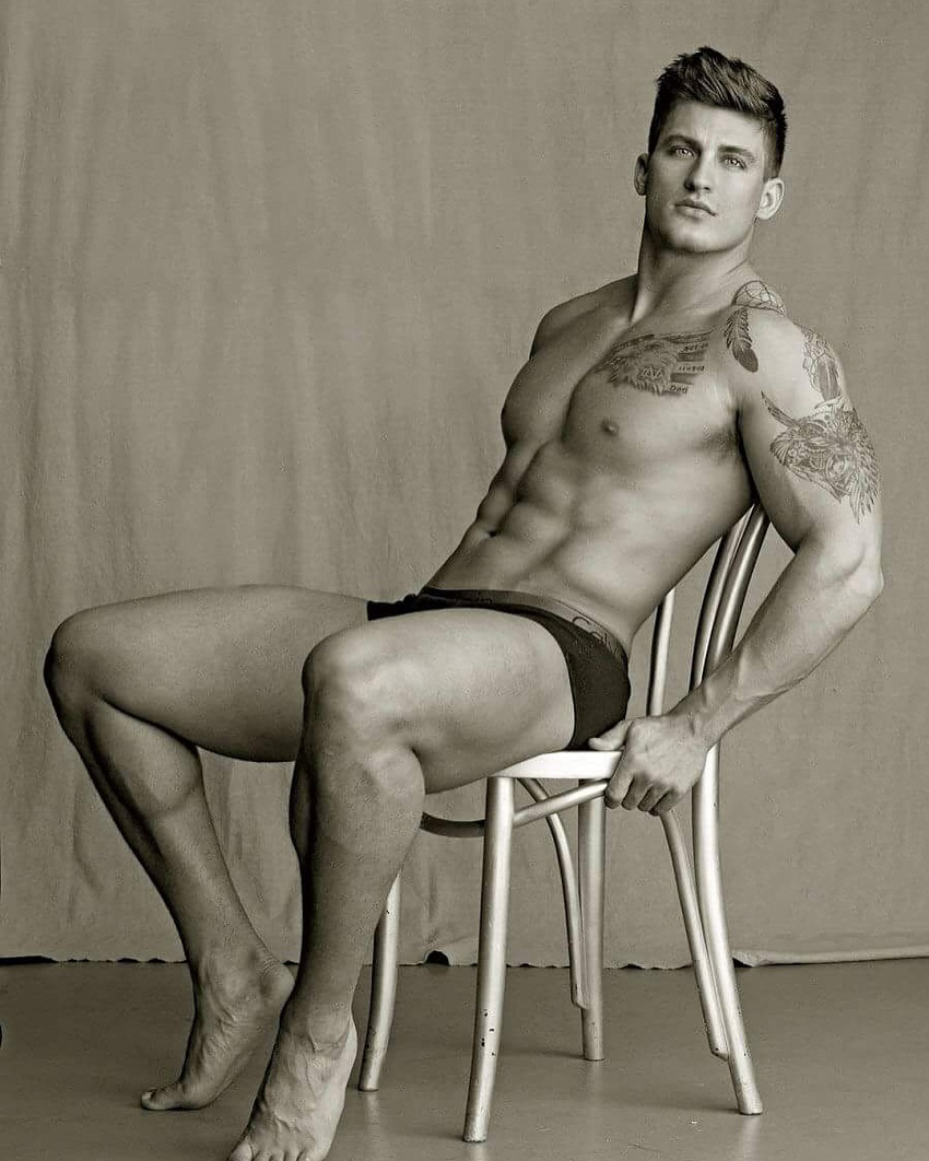 Quinn Biddle sitting shirtless on a chair posing in a modeling photo shoot