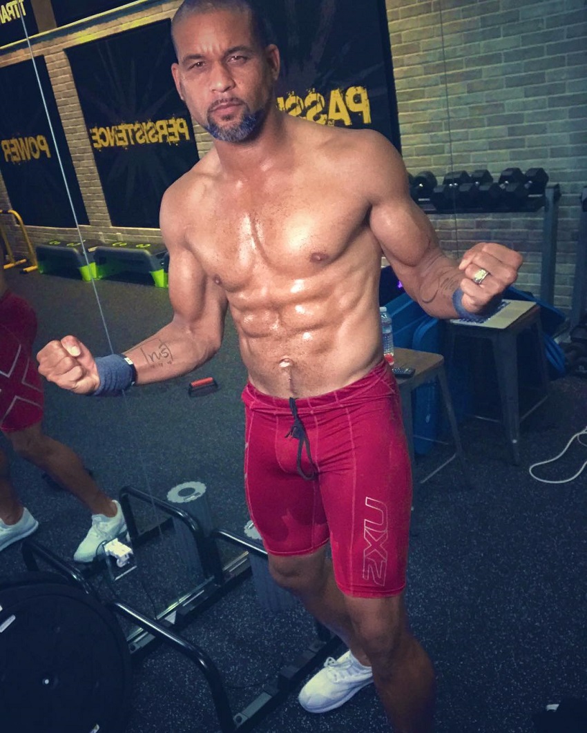 Shaun T flexing his shirtless upper body for a photo