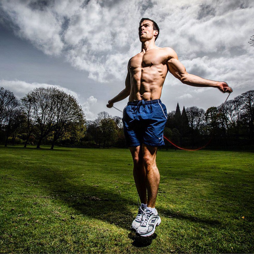 Scott Baptie performing jumping ropes shirtless in the grass field