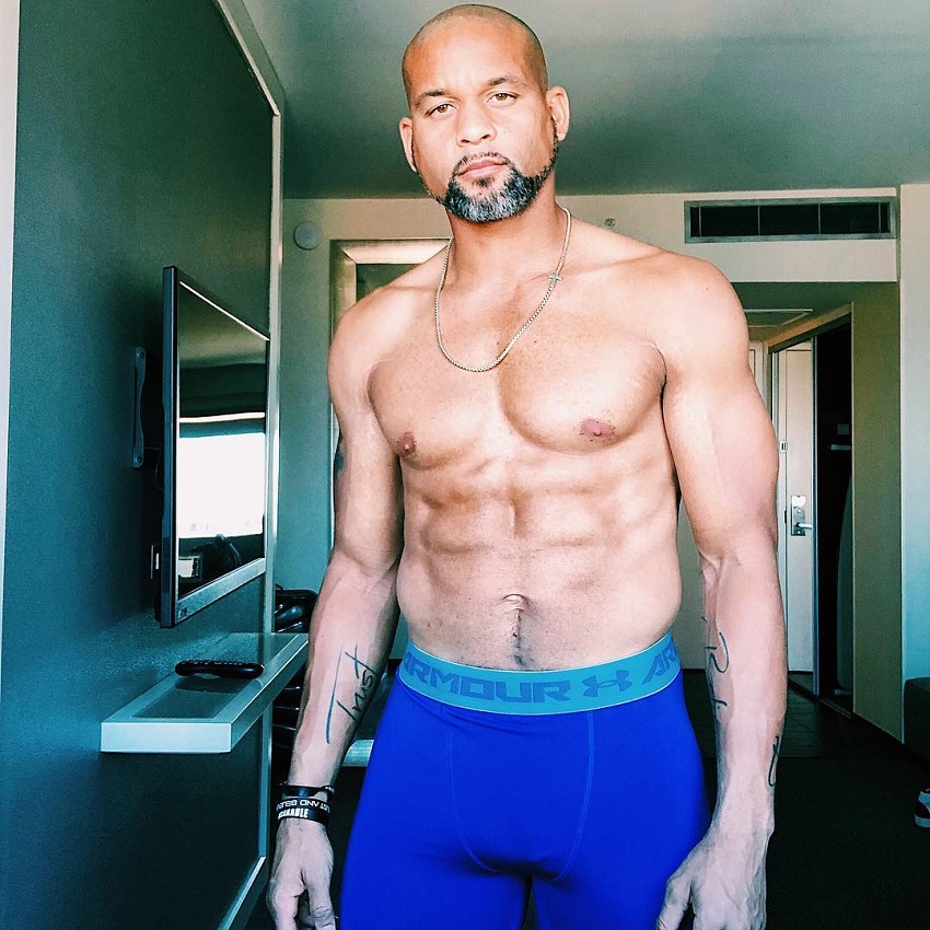 Shaun T displaying his shirtless upper body for the camera looking strong and lean