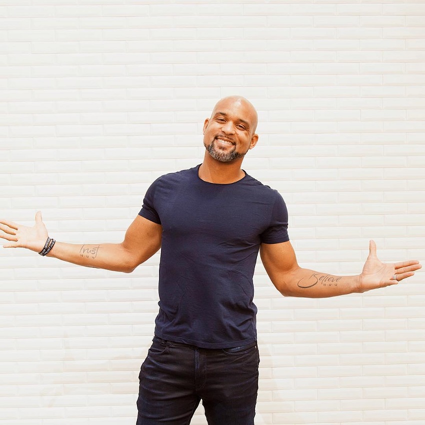 Shaun T posing in his dark blue t-shirt, looking healthy and strong