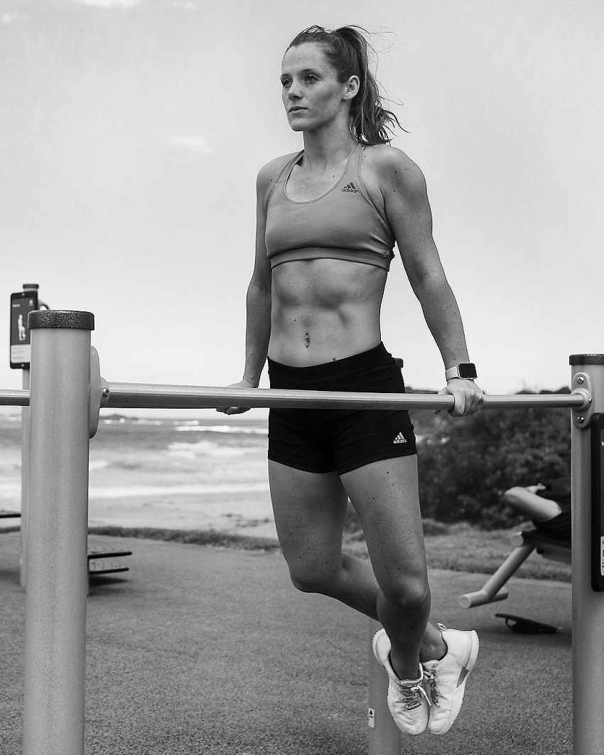 Tanya Poppett performing dips outdoors by a beach