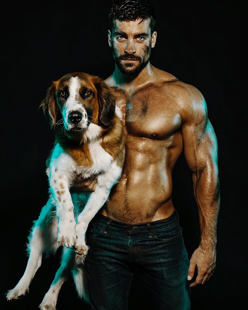 Thomas Canestraro posing shirtless with a dog in his arms looking muscular and ripped