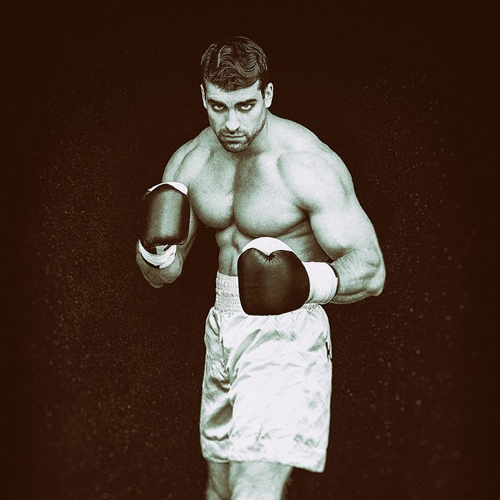 Thomas Canestraro posing shirtless in a photo shoot wearing boxing gloves