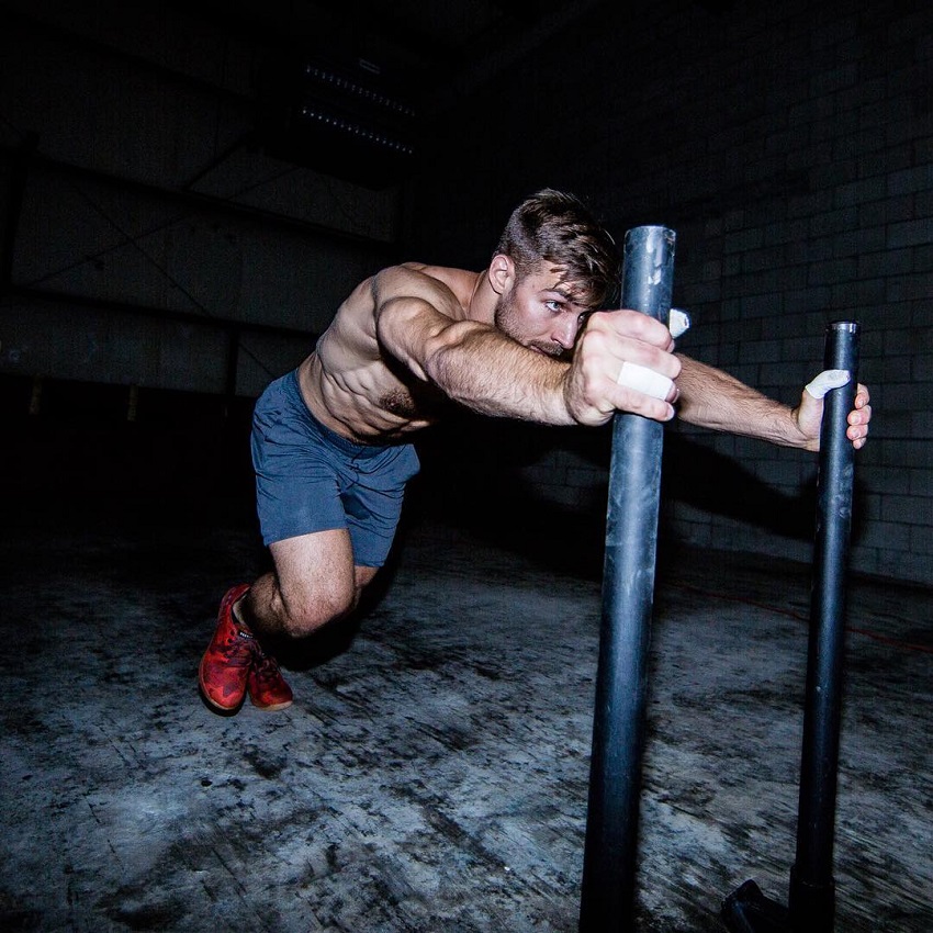 Alex Anderson pushing a cart with weights looking strong and fit