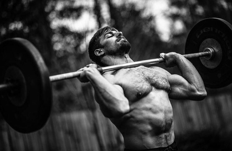 Alex Anderson lifting a heavy barbell while being shirtless, looking strong and ripped