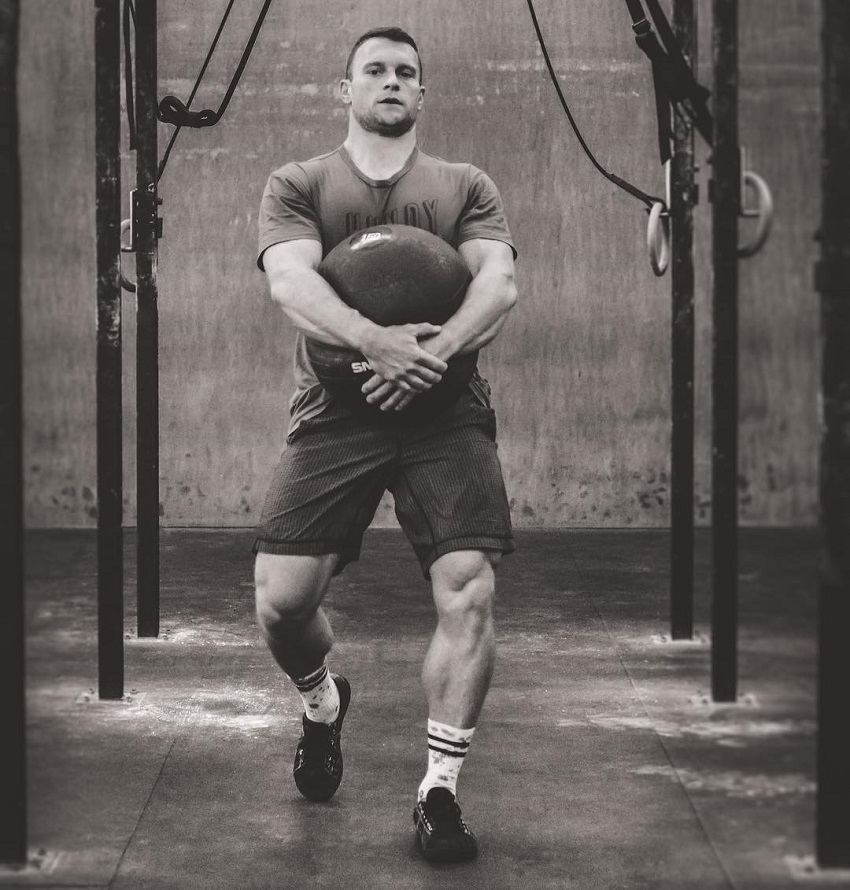 Chad Mackay carrying a heavy ball during CrossFit training looking strong and fit