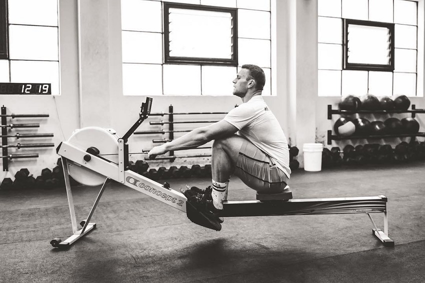 Chad Mackay sitting in a CrossFit gym doing an exercise on a machine