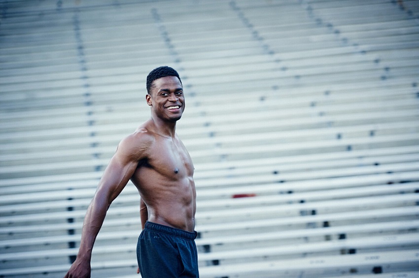 Joe Holder posing shirtless for a photo and smiling