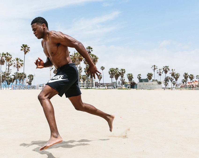 Joe Holder running shirtless on the beach