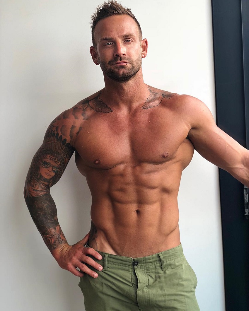 Joel Bushby posing shirtless for a photo looking lean and muscular