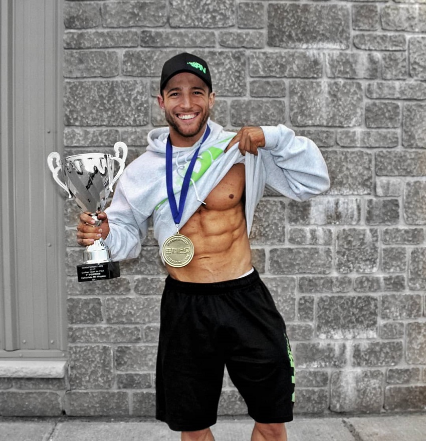 Jonathan Plante flexing his abs under a shirt and posing with a medal and trophy